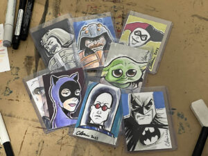 Several different cards, each with a different drawing on it, lie haphazardly atop a wood surface.